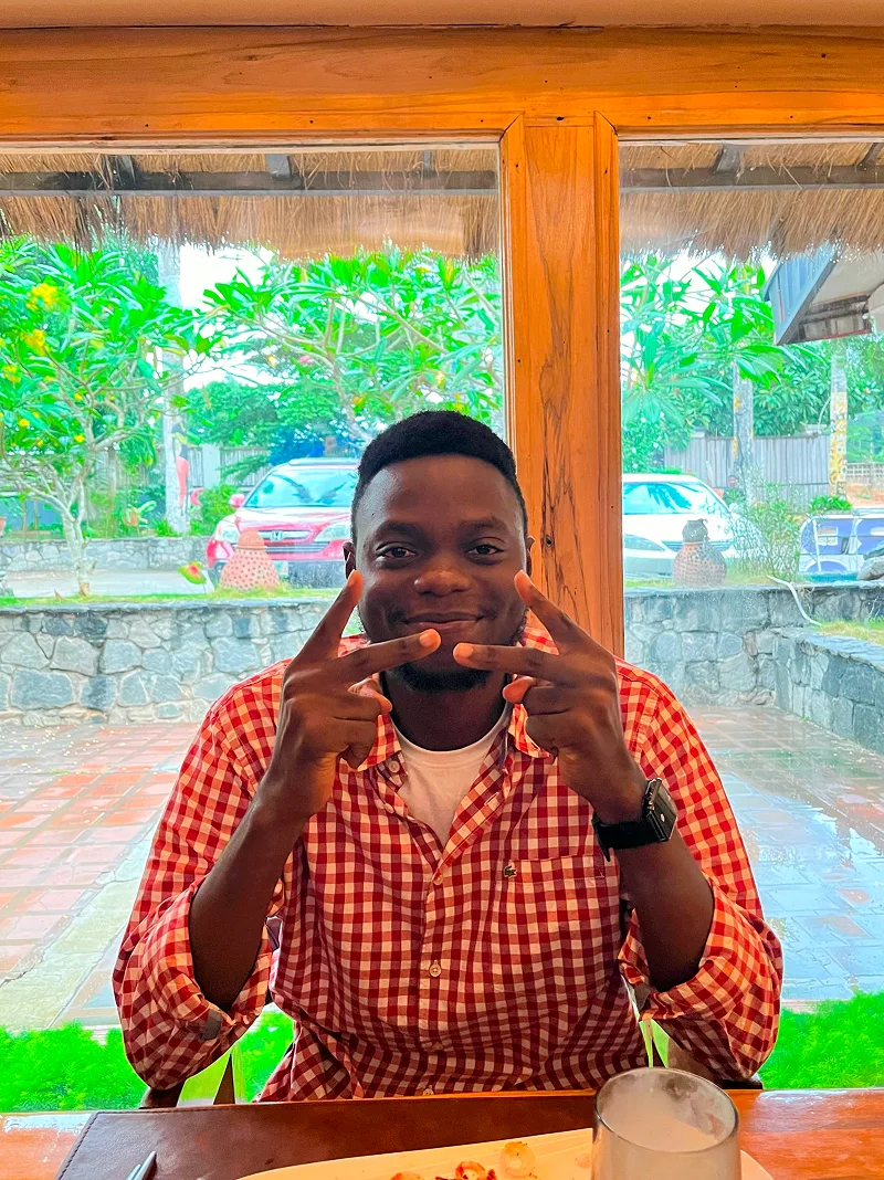 Olumide smiling at a table outdoors